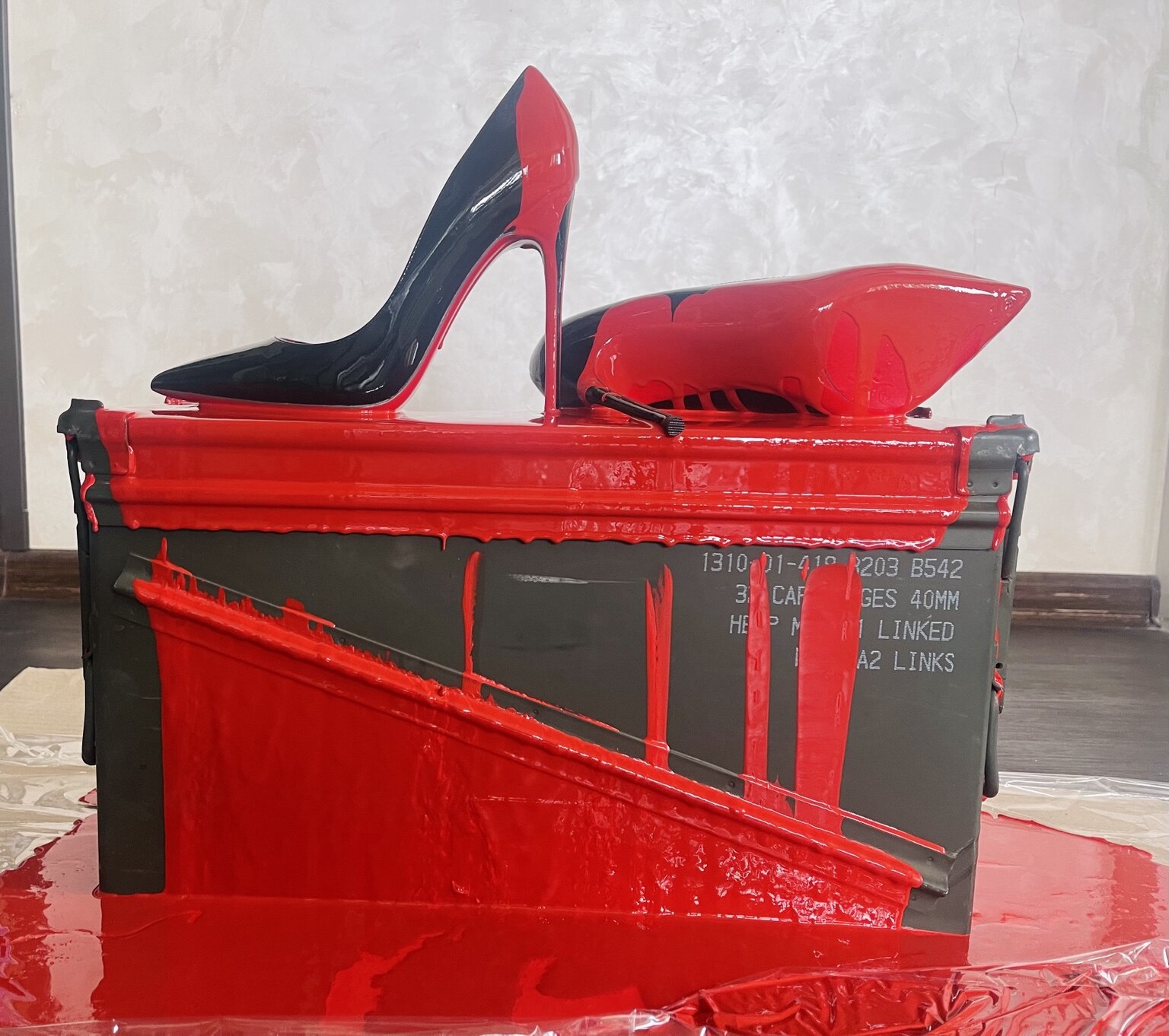 Red installation made from an ammunition box with high-heeled shoes