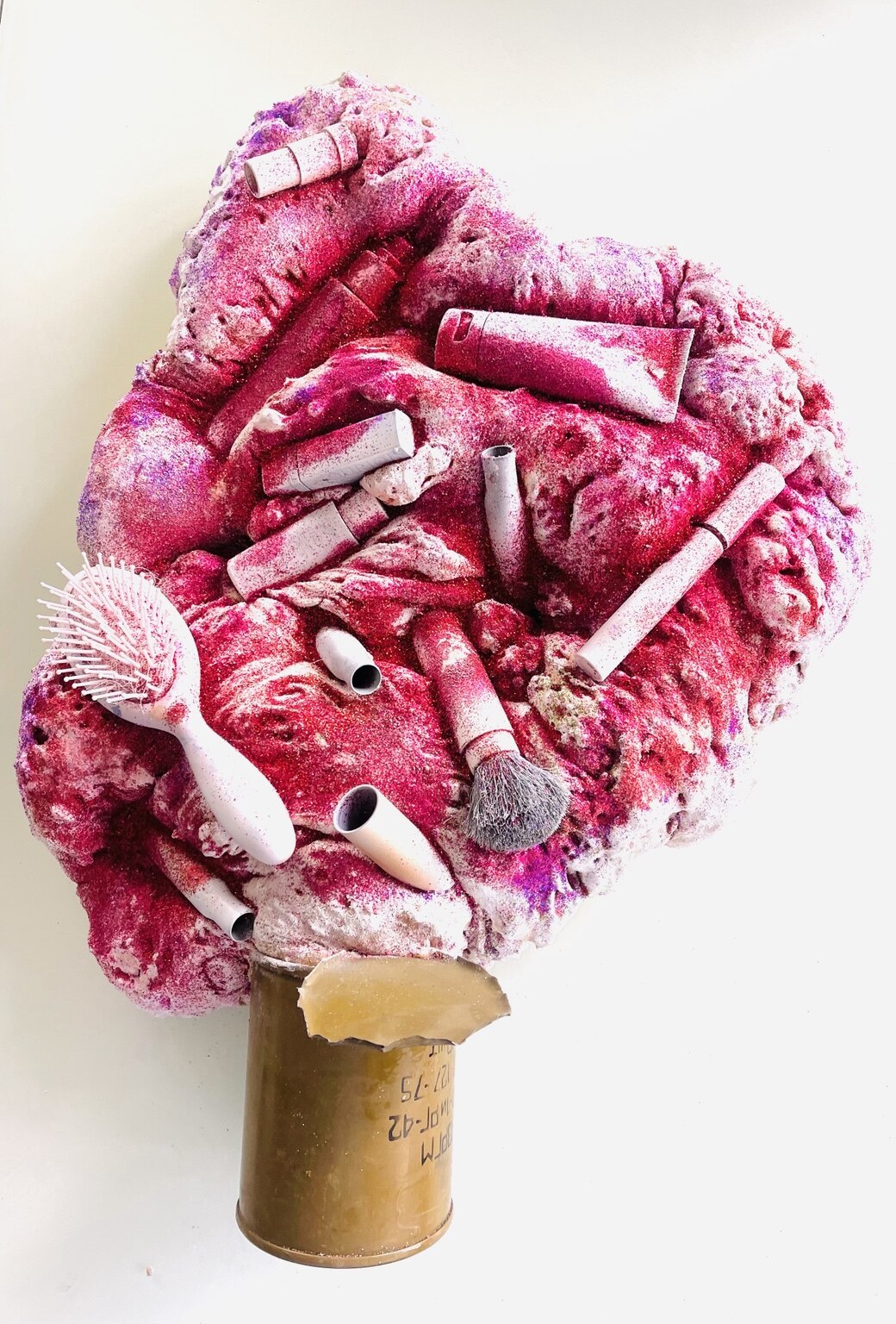 Pink sculptural installation with cosmetics and a shell casing